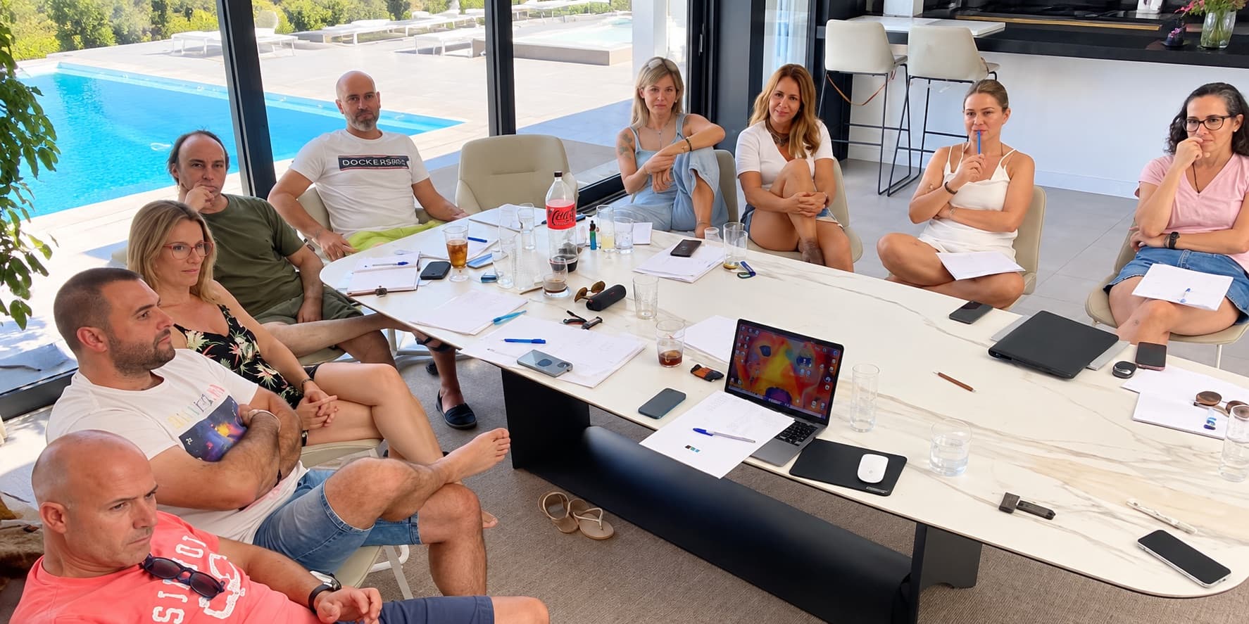 Réunion de travail autour de la table du salon, avec vue sur la piscine