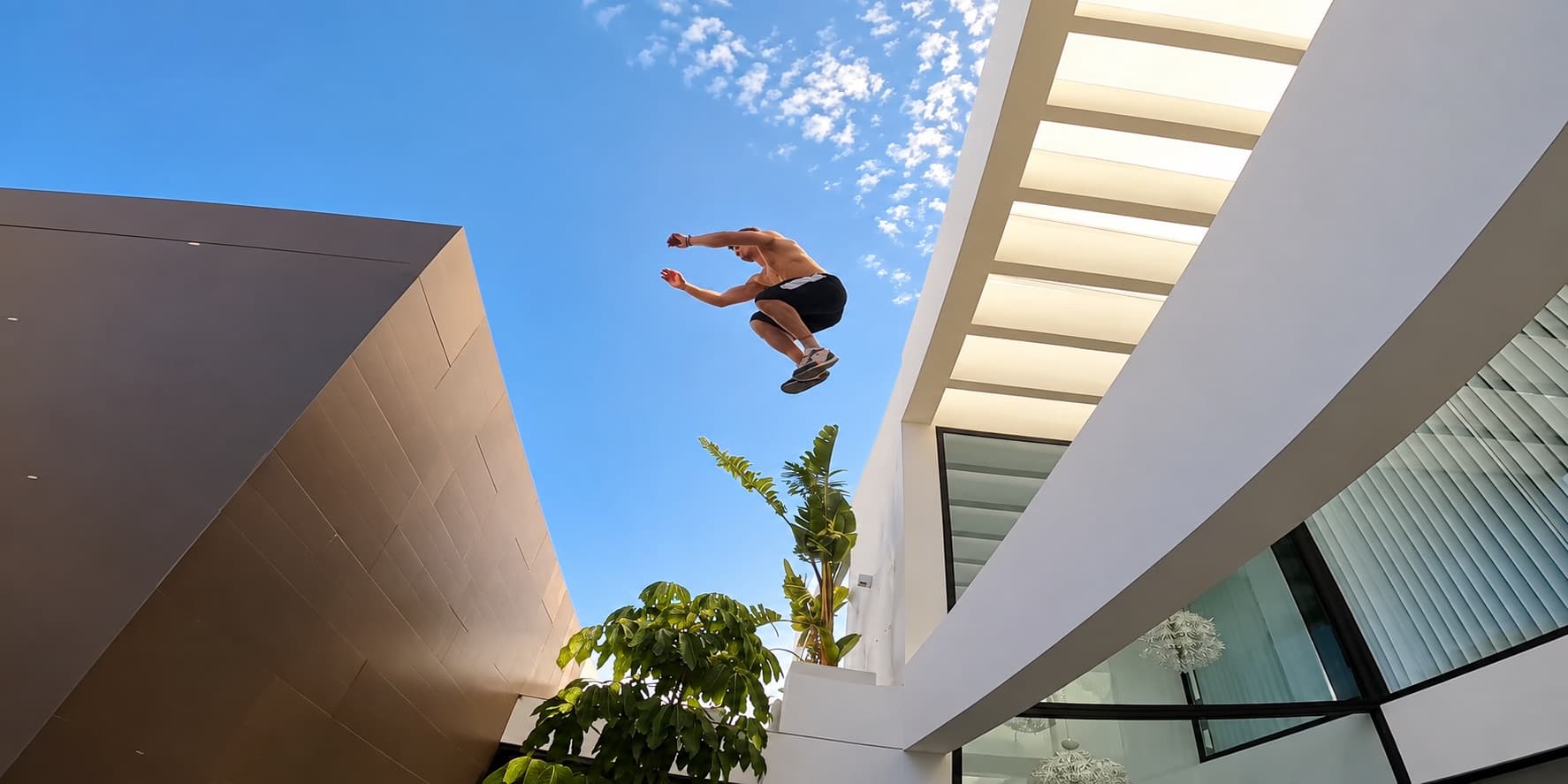 Saut de parkour au-dessus du patio intérieur de la villa, entre la façade et la pergola