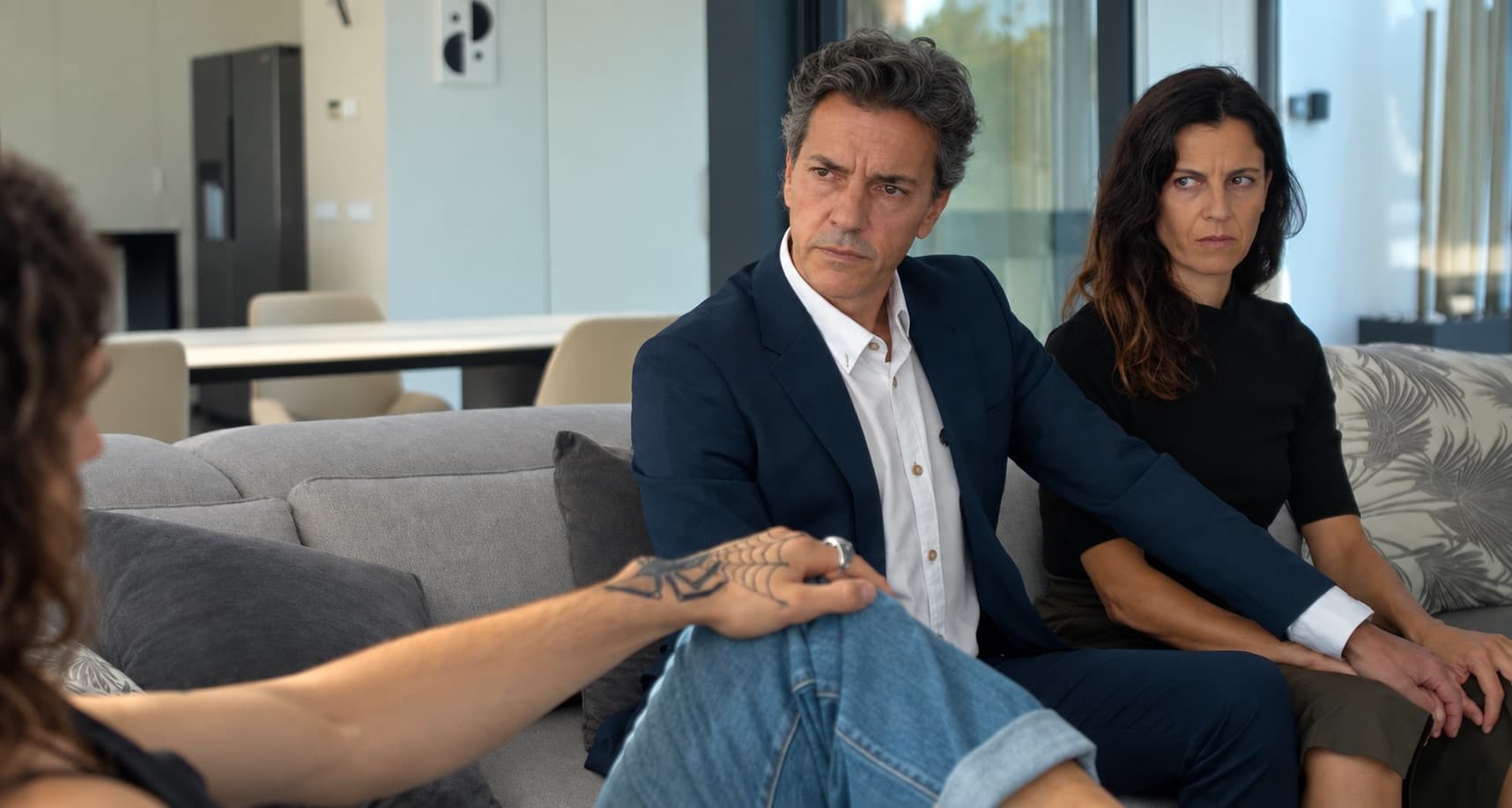 Scène de tournage sur le canapé du salon, avec les baies vitrées en fond