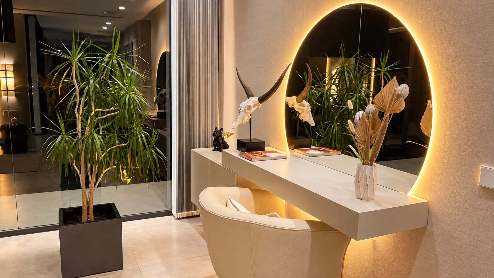 Coiffeuse avec miroir rond éclairé, crâne à cornes et plante à gauche