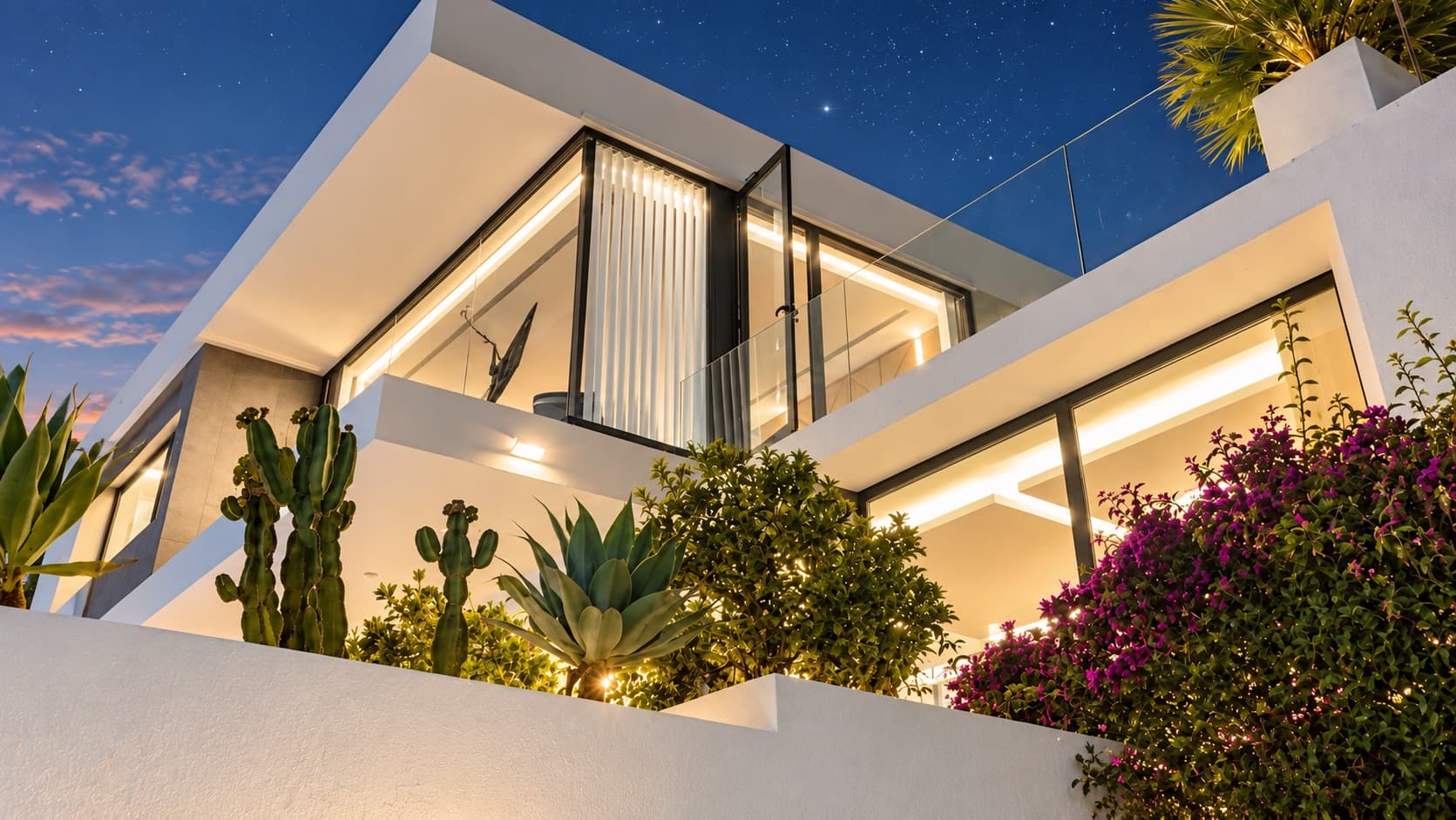 Villa Los Pichies façade lit up at dusk with a cactus garden