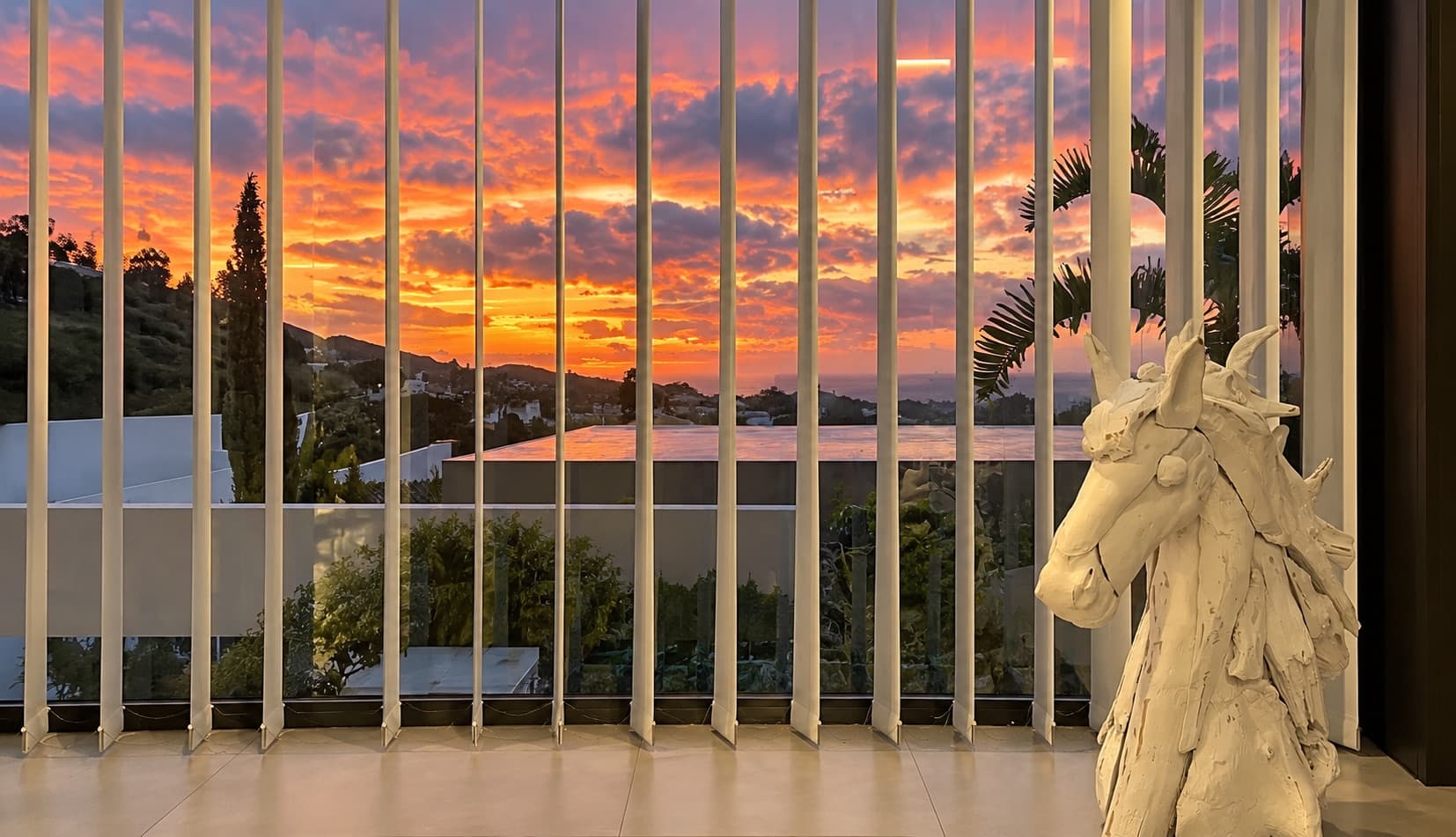 Coucher de soleil vu entre les lames verticales, avec une sculpture de chevaux