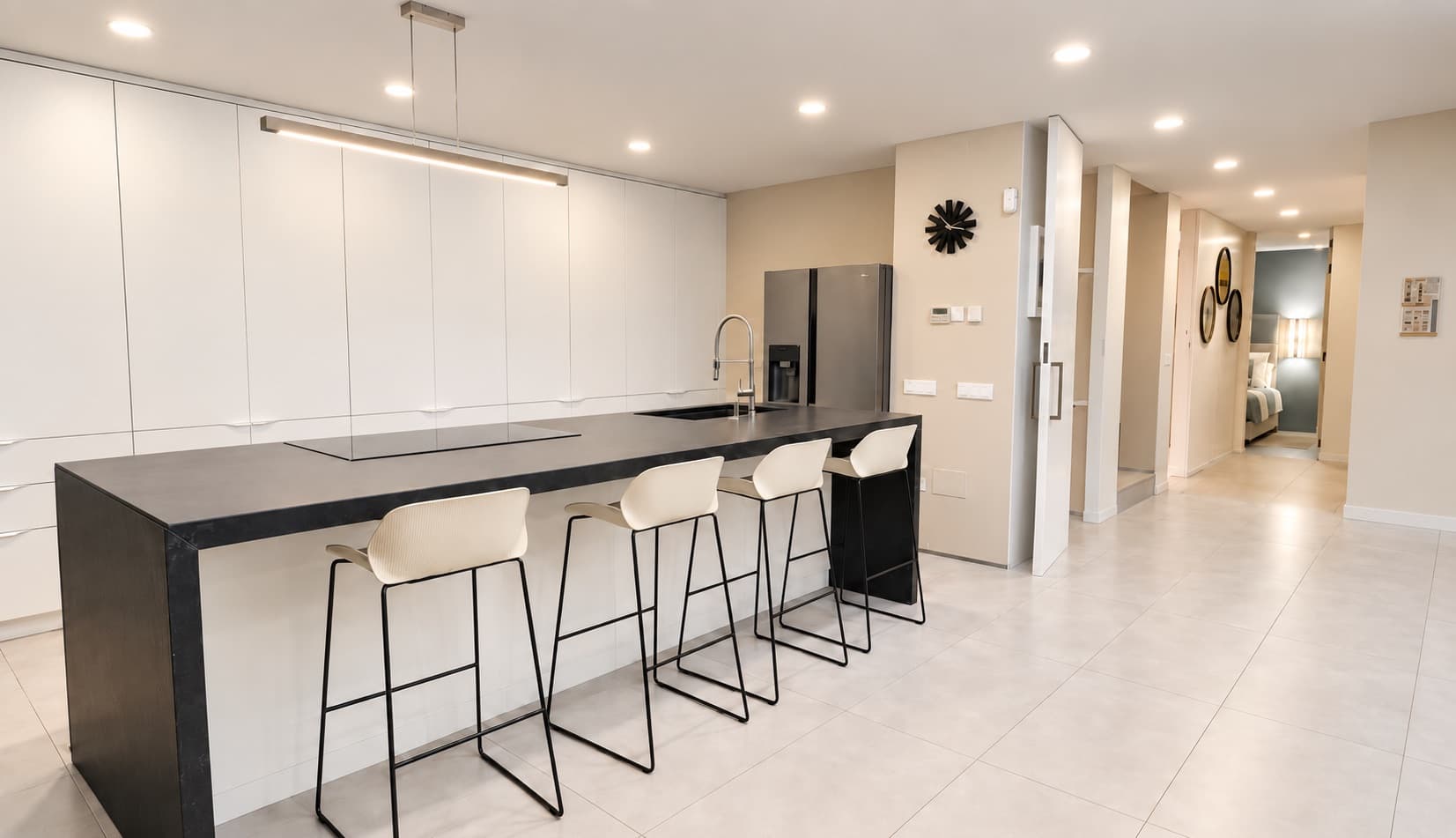 Îlot de cuisine avec tabourets hauts et couloir menant à la chambre au fond